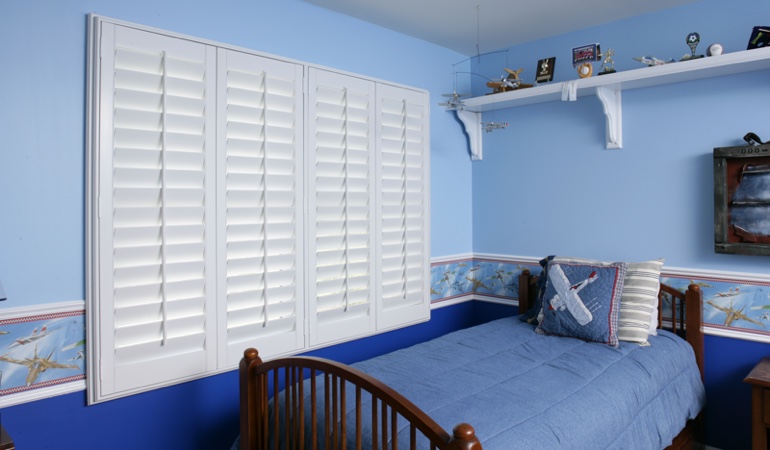 Large plantation shutters covering window in blue kids bedroom in Detroit 